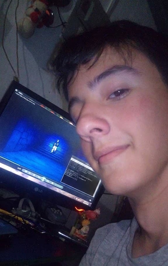 Una selfie de cerca en la noche, iluminado por el monitor de al lado con un juego pausado en pantalla.